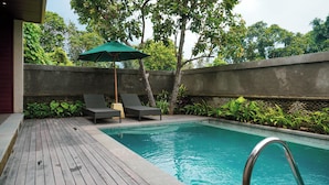 A swimming pool with two lounge chairs and a green umbrella. - Naata Villas Ubud (Sukawati)
