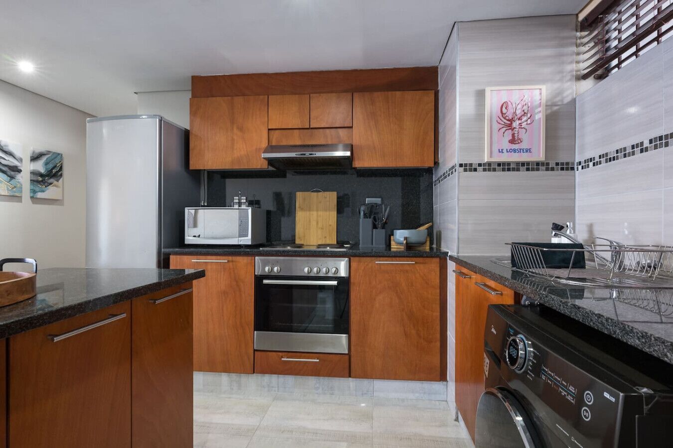 A modern kitchen with wooden cabinets, a stainless steel oven, a microwave, and a dishwasher.
