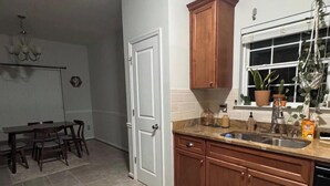 A kitchen with wooden cabinets, a sink, and a window with plants. - Private Room & Bath in Augusta (Augusta)