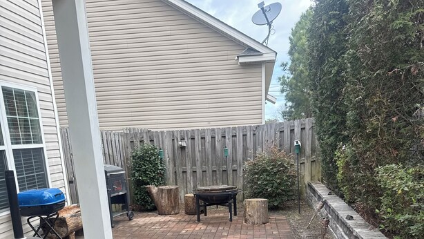 A backyard with a brick patio, a grill, a wooden fence, and a satellite dish. - Private Room & Bath in Augusta (Augusta)