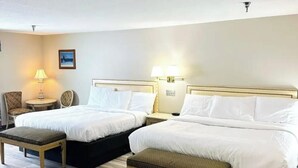 Een hotelkamer met twee bedden, een kleine tafel, een stoel en een bank.