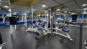 Une salle de sport équipée de divers appareils d’exercice, de miroirs et offrant un environnement propre et bien éclairé.