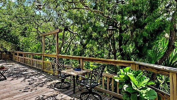 Una terrazza in legno con mobili da esterno, immersa nel verde.