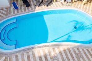 Ein Schwimmbecken mit gefliestem Sonnendeck und Liegestühlen.