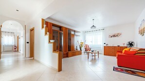 Ein geräumiges Wohnzimmer mit einem roten Sofa, Holzschränken und einem Essbereich mit Tisch und Stühlen.