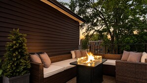 An outdoor seating area with a fire feature, wicker furniture, and a potted plant.