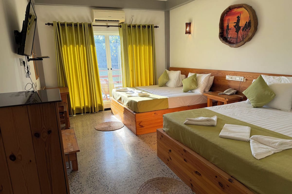 A hotel room with two beds, a wooden headboard, a small table, a telephone, and a wall-mounted artwork.