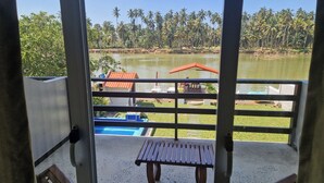 Un balcón con vistas a un lago, una piscina y un edificio con techo rojo.