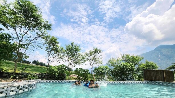 A clear pool surrounded by stone steps and trees, with a mountainous backdrop. - My Garden Villa (Ta Van)