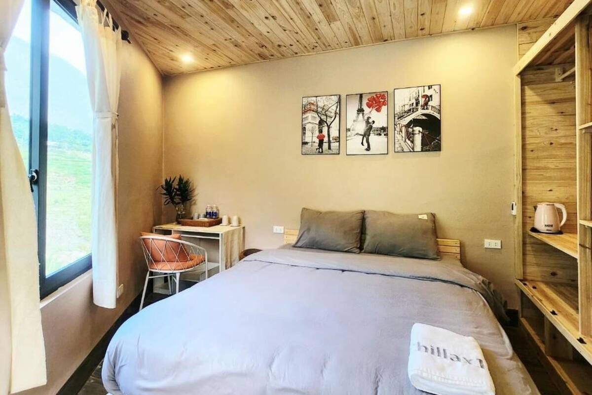 A bedroom with a bed, a desk, and a chair. There are three artworks on the wall.