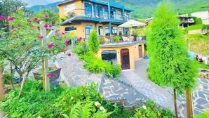 A two-story building with a balcony, surrounded by lush greenery and a mountainous backdrop. - My Garden Villa (Ta Van)
