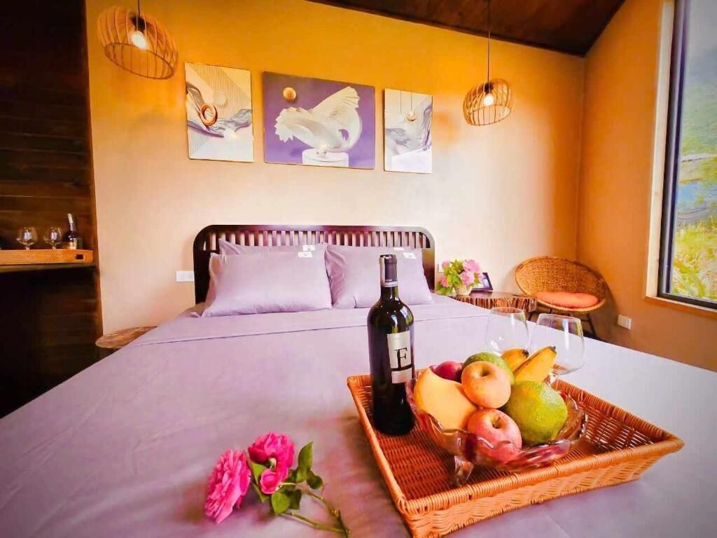 Un dormitorio con una cama, una cesta de mimbre con fruta, una botella de vino y cuadros en la pared.