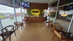 A restaurant with a bar area, wooden furniture, and large windows offering a view of the city. - SANERA Villa by SATYA Hospitality (Wonosobo)