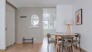 Una zona d'esmorzar moderna amb una taula rodona i quatre cadires, una làmpada de peu i una obra d'art abstracta penjada a la paret.