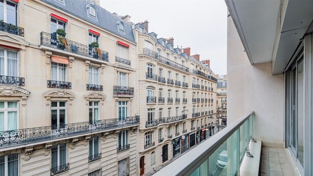 Filera d'edificis parisins clàssics amb balcons ornamentats i finestres grans.