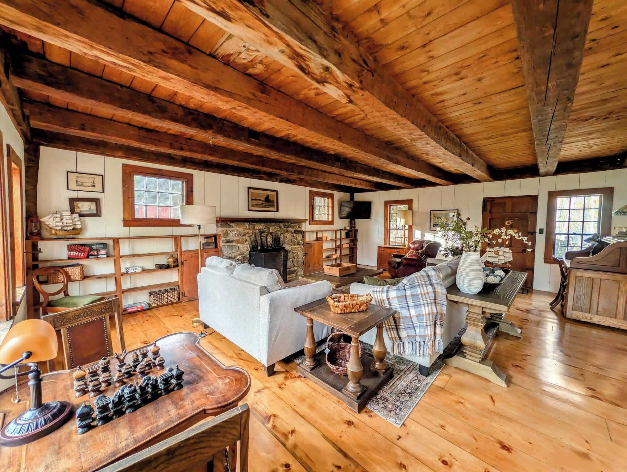 Ein gemütliches Blockhäuschen-Interieur mit Holzdielen, Kamin, Sofa, Couchtisch und einem Schachbrett.