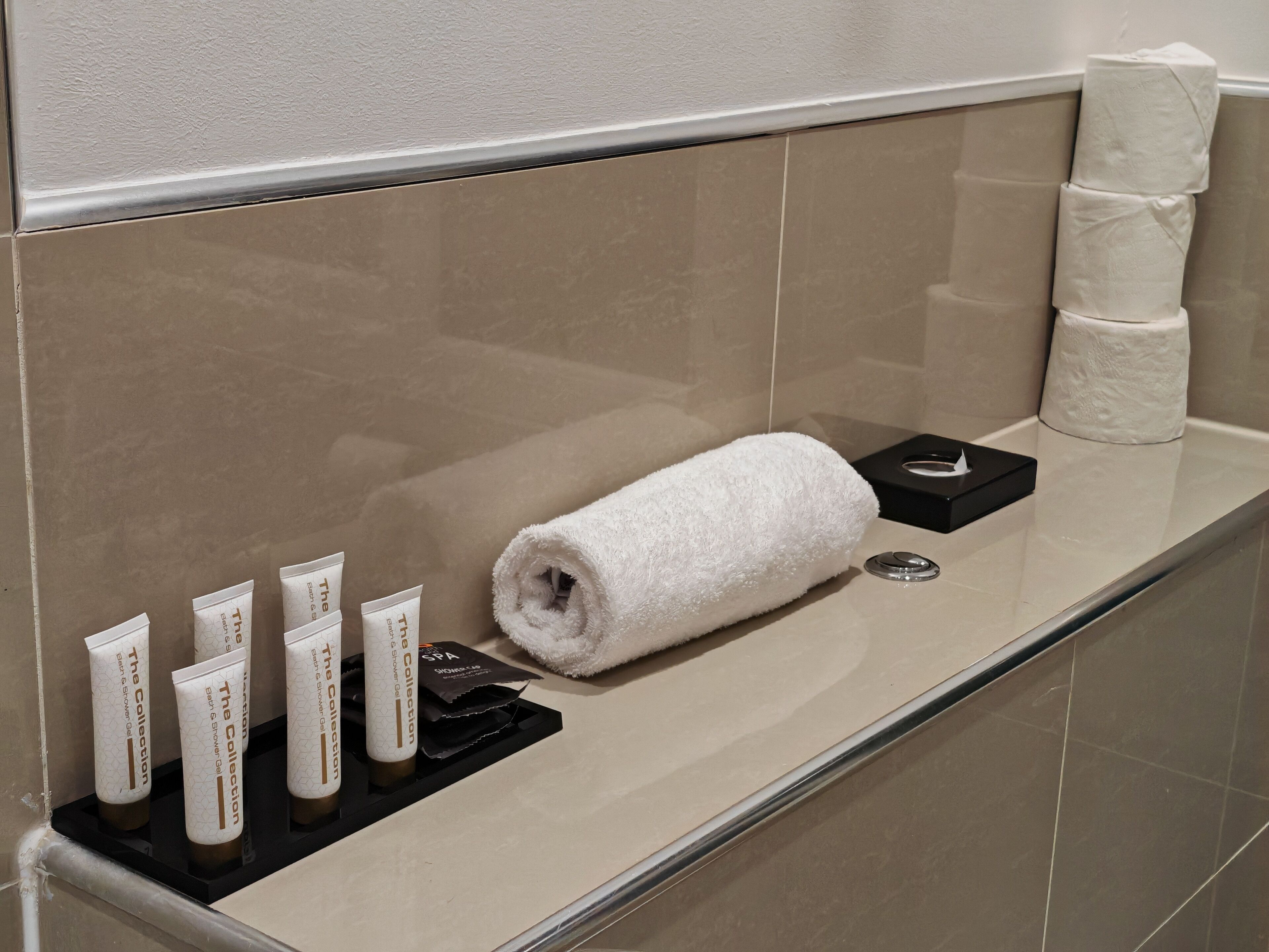 Un bagno con asciugamano, articoli da toilette e dispenser di carta igienica.