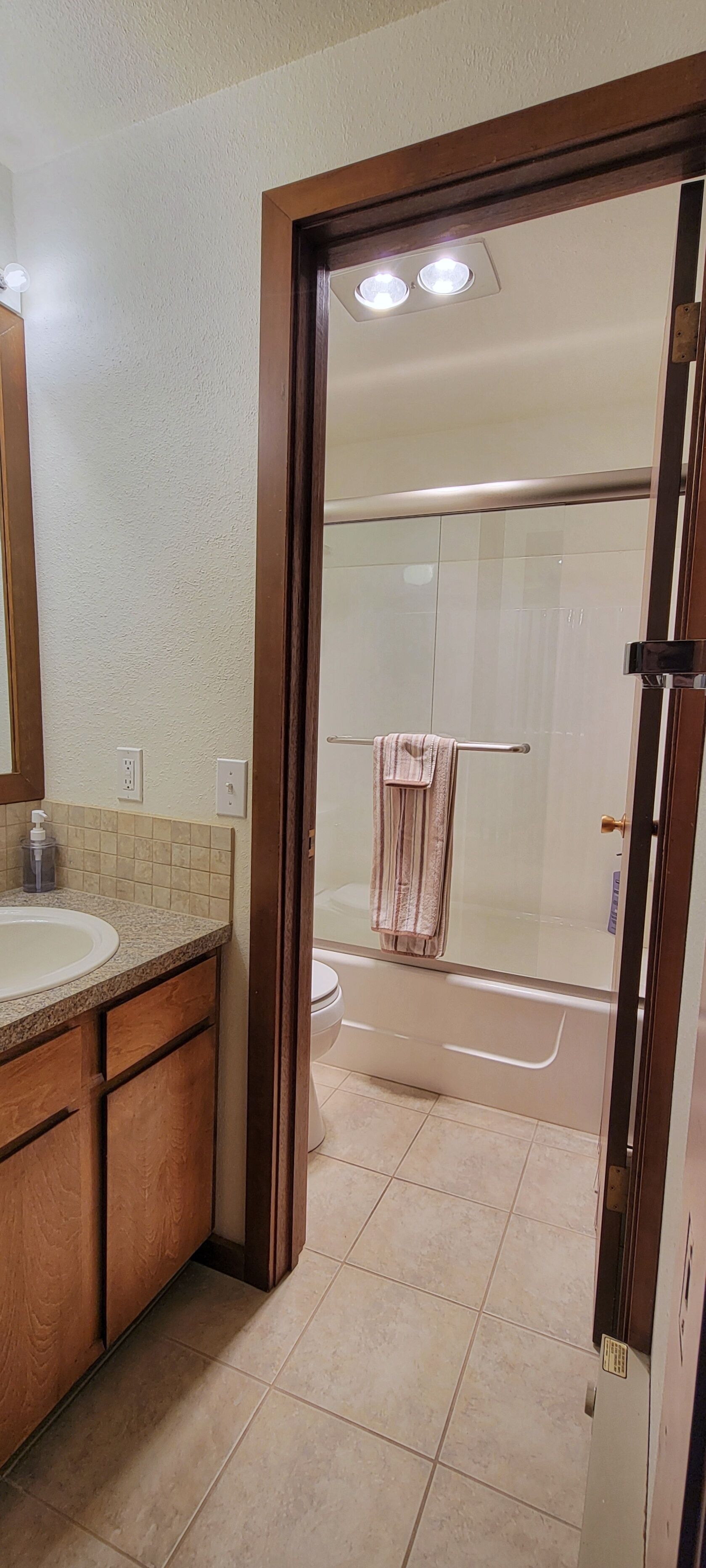 A bathroom with a wooden vanity, a sink, and a glass shower enclosure.