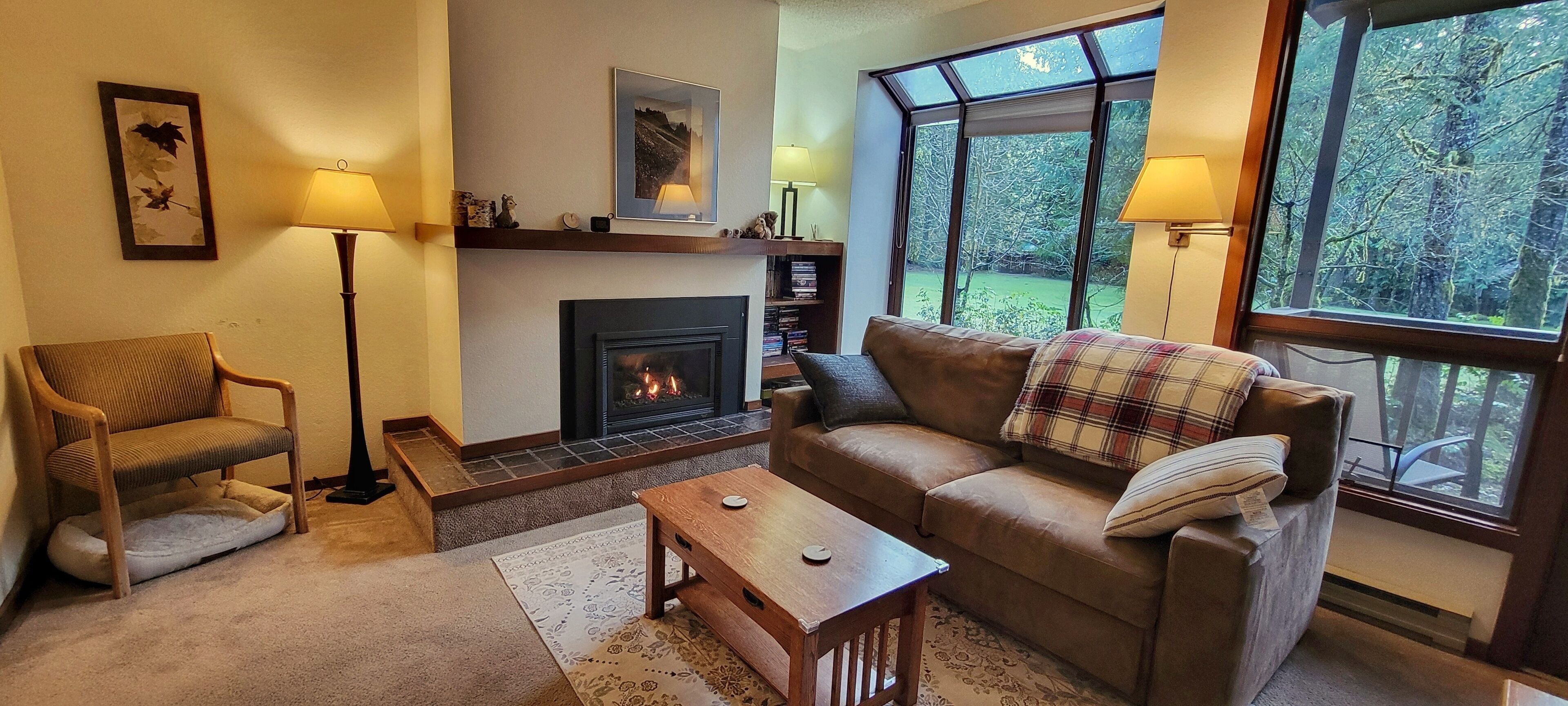 A cozy living room with a fireplace, a sofa, a chair, and a coffee table.