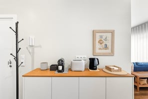 Eine Küchenzeile mit Kaffeemaschine, Toaster, Wasserkocher und einem gerahmten Bild an der Wand.
