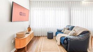 Ein modernes Wohnzimmer mit einem dunkelbraunen Ledersofa, einem Holztischchen und einem großen Fenster mit weißen Jalousien.