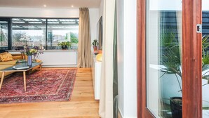 A spacious living room with a large window, a sofa, a coffee table, and a rug. - 4 Star Holiday Home in Viborg (Viborg)