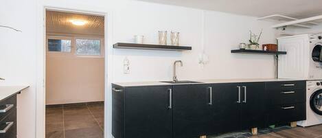 A modern kitchen with a black cabinet, a built-in washing machine, and a window with a view.