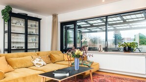 A living room with a yellow sofa, a black coffee table, and a large window with a view of greenery. - 4 Star Holiday Home in Viborg (Viborg)