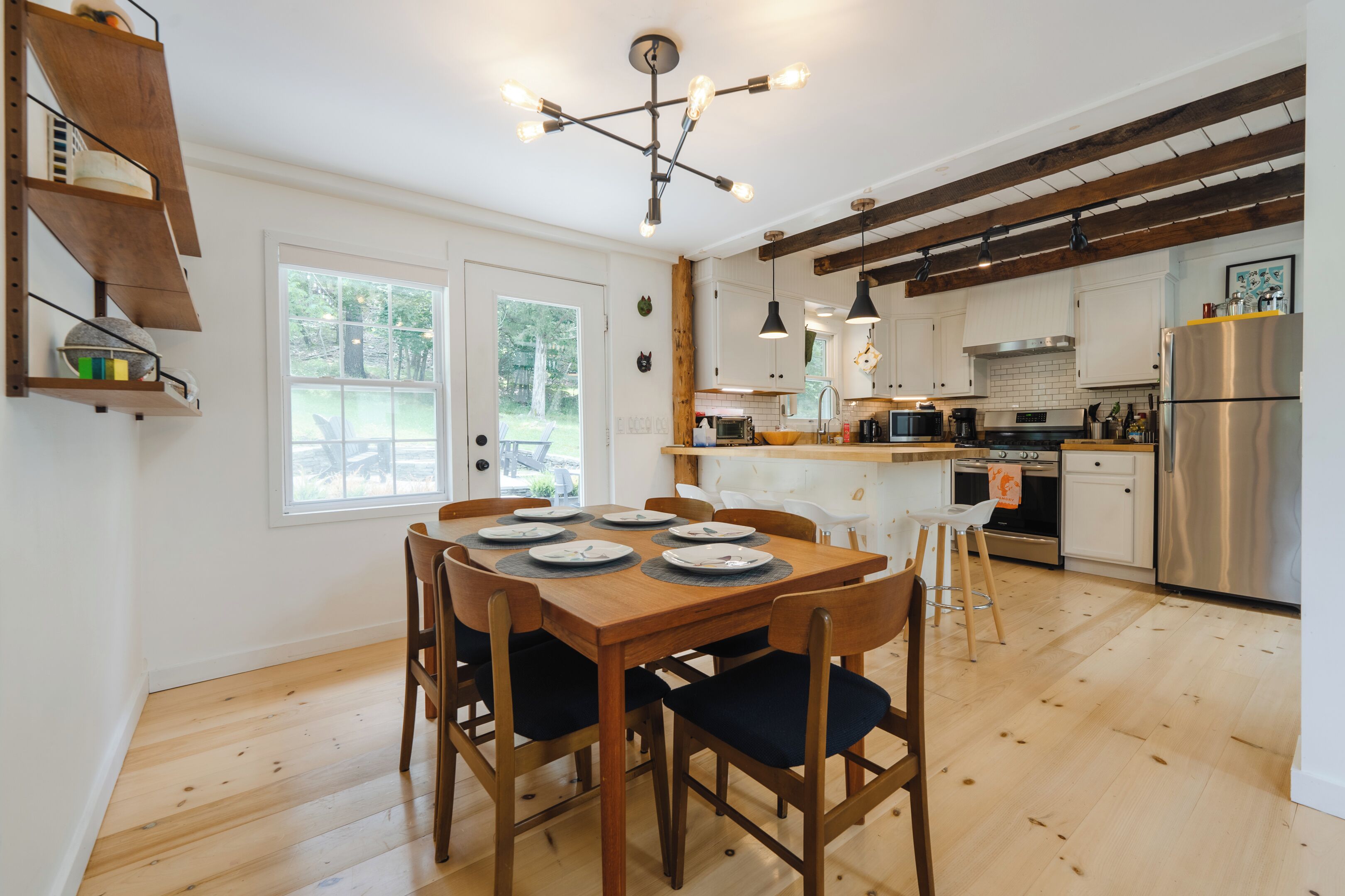 Una cocina moderna con piso de madera, una mesa de comedor preparada para seis personas y una isla grande con electrodomésticos.