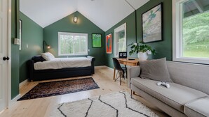 Un dormitorio con cama, escritorio, sofá y un amplio ventanal.