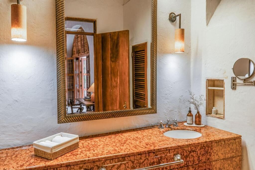 Een badkamer met een grote spiegel, een wastafel en een badkamermeubel.
