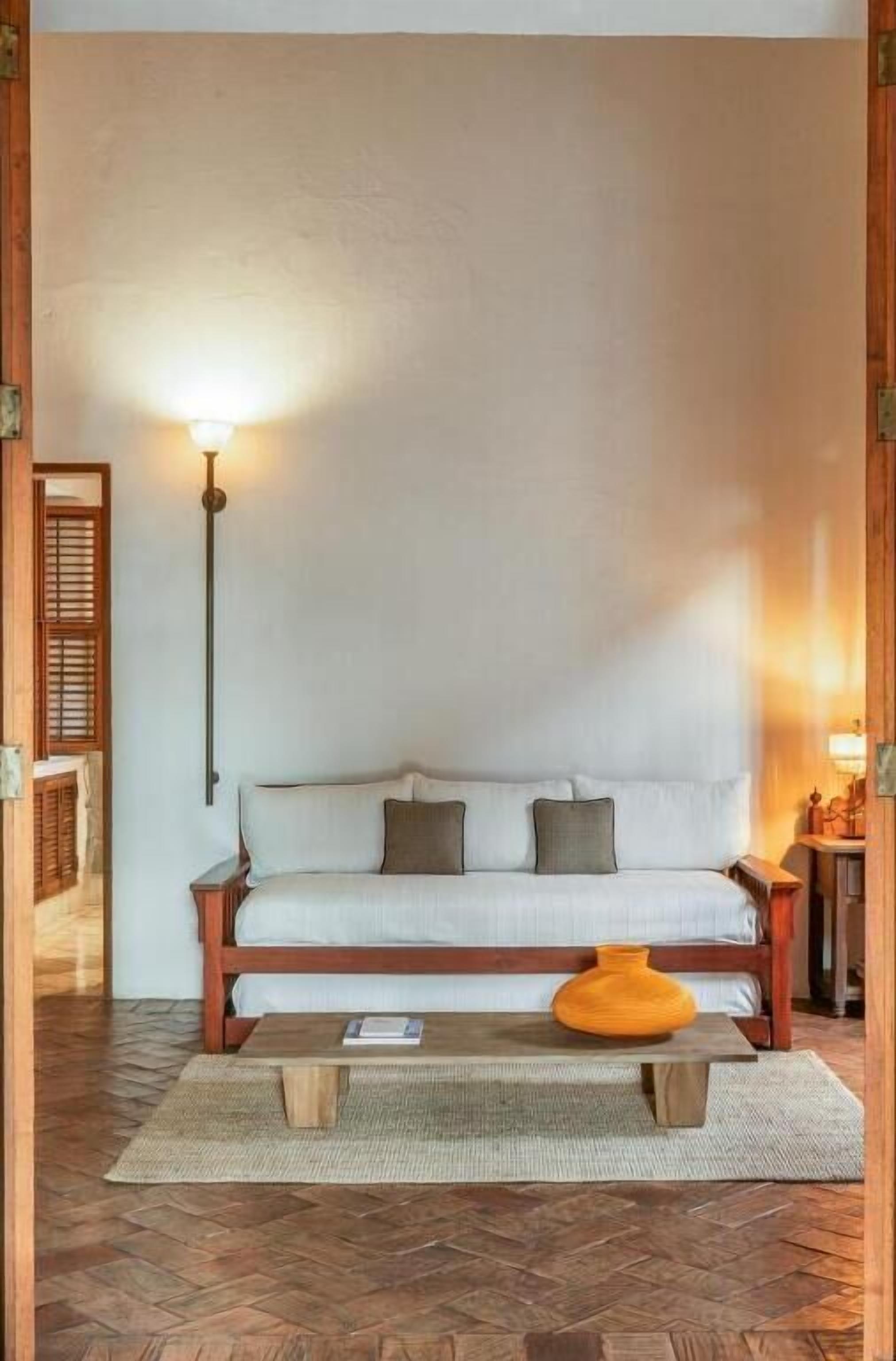 Una habitación acogedora con un sofá, una mesa de centro de madera y una lámpara.
