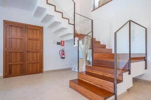 Un interior moderno con una escalera de madera, un extintor y un doble puerta.