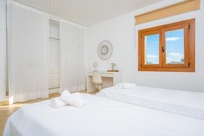Un dormitorio con dos camas, un escritorio y una ventana con contraventanas de madera.