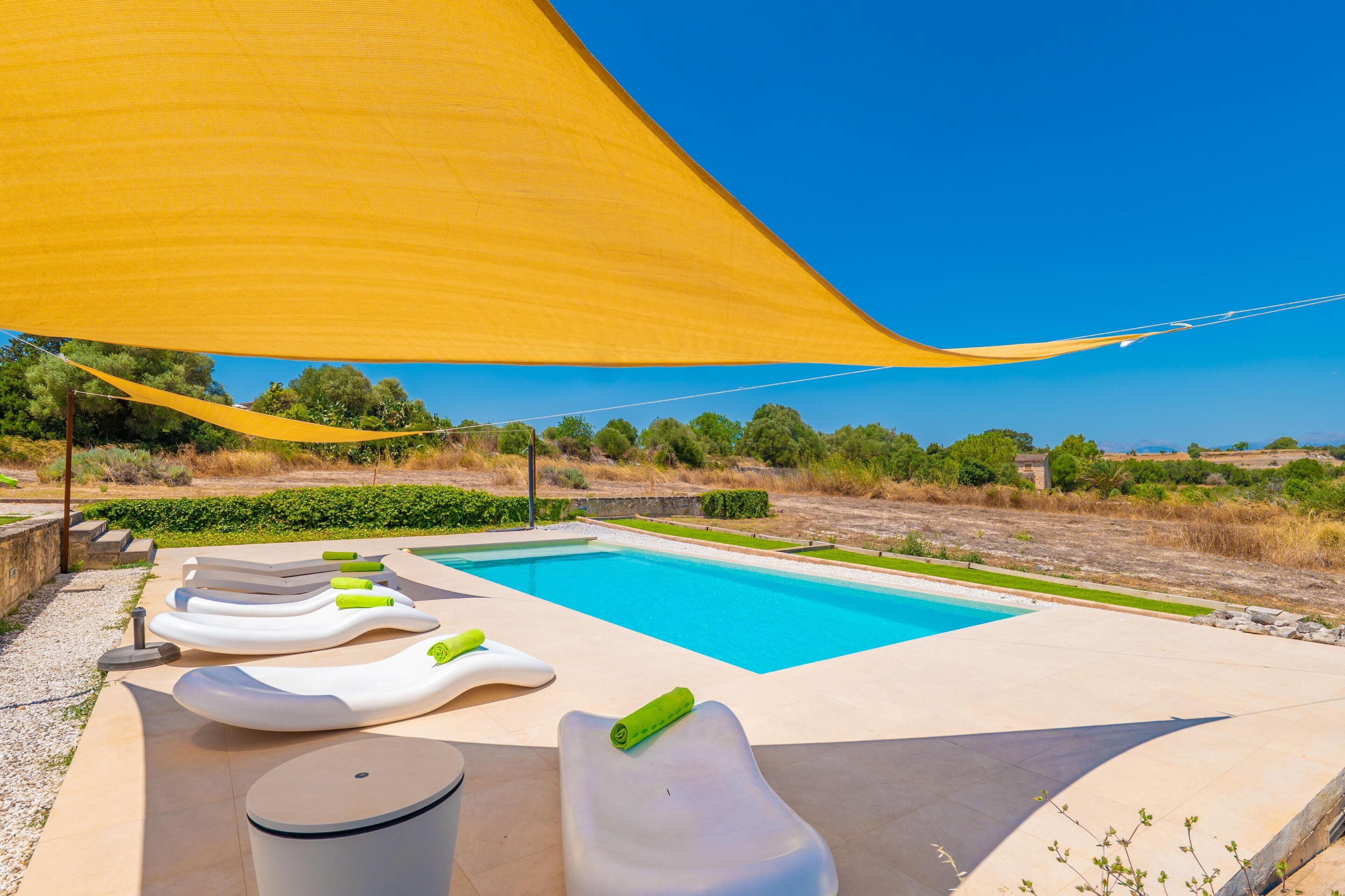Una piscina con sillones de descanso y un parasol.