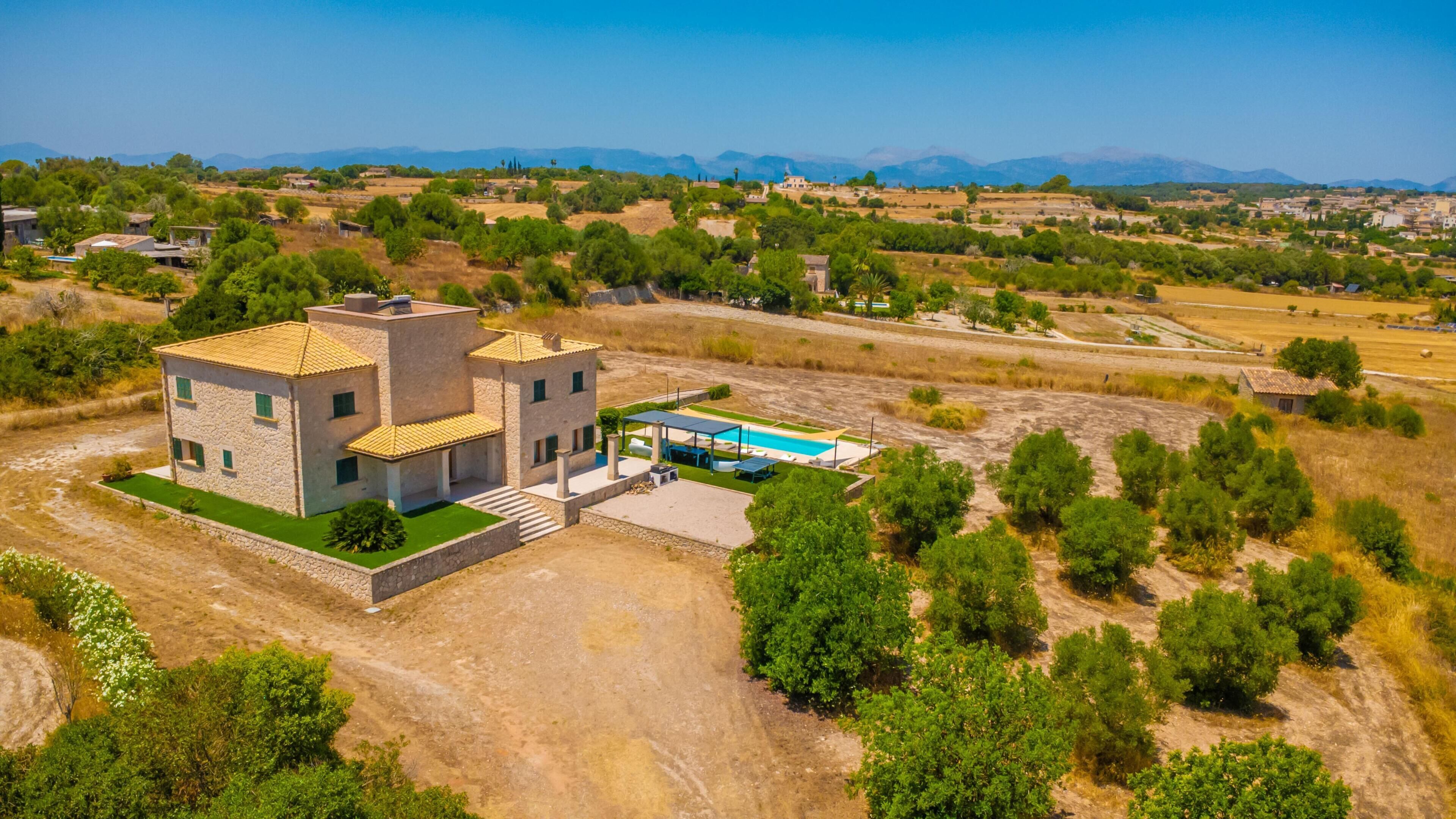 Una casa moderna de dos pisos con piscina, rodeada de paisaje rural.
