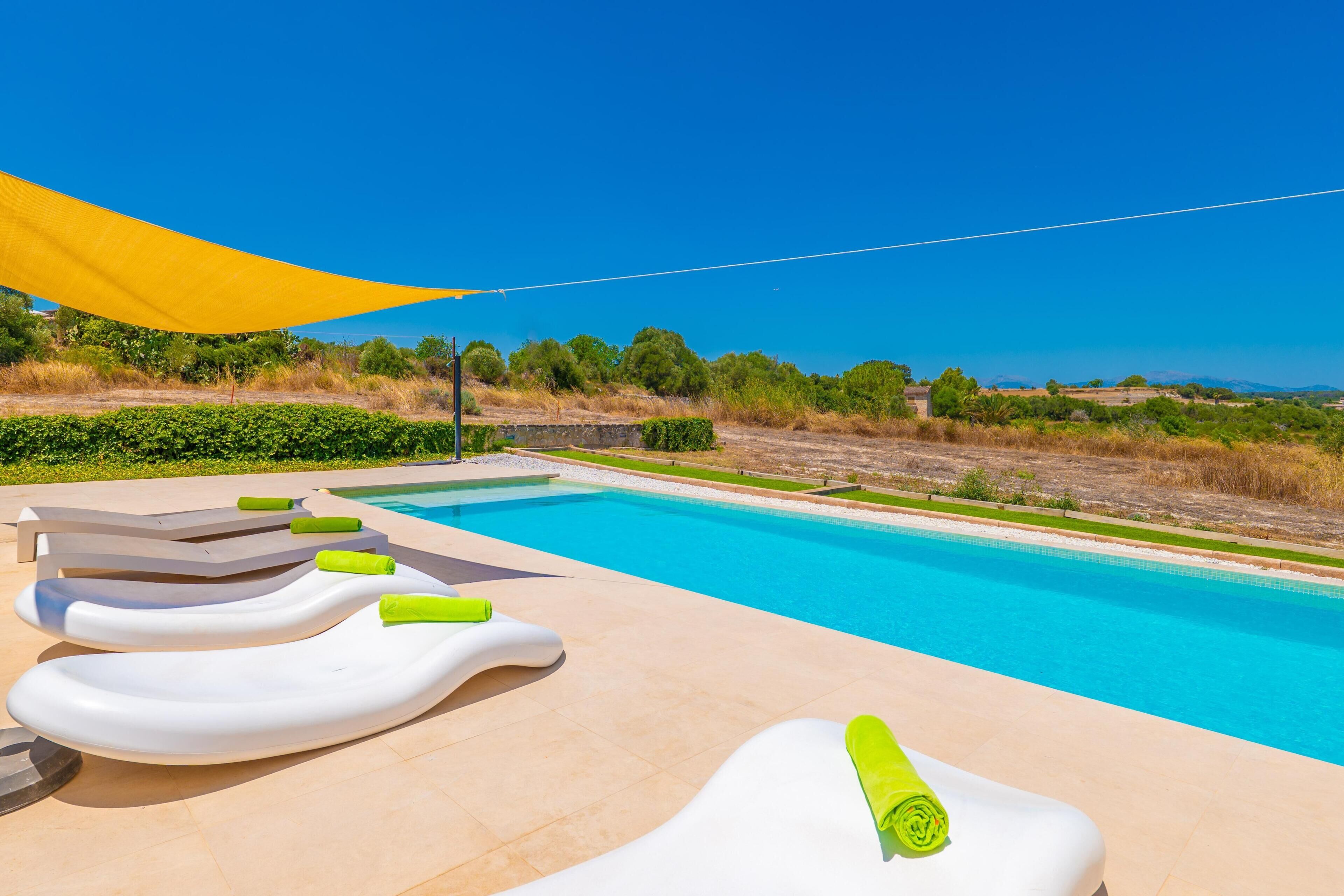 Una piscina con sillas de descanso y un toldo amarillo.