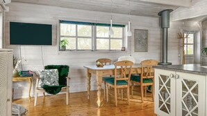 A cozy kitchen with wooden cabinets, a dining table with chairs, a stove, and a window with a view of trees. - Beautiful home in Vordingborg with WiFi (Vordingborg)