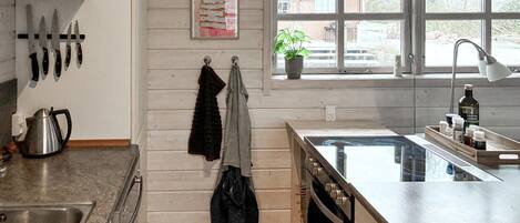 A kitchen with wooden walls, a window with a view, a sink, and a stove.
