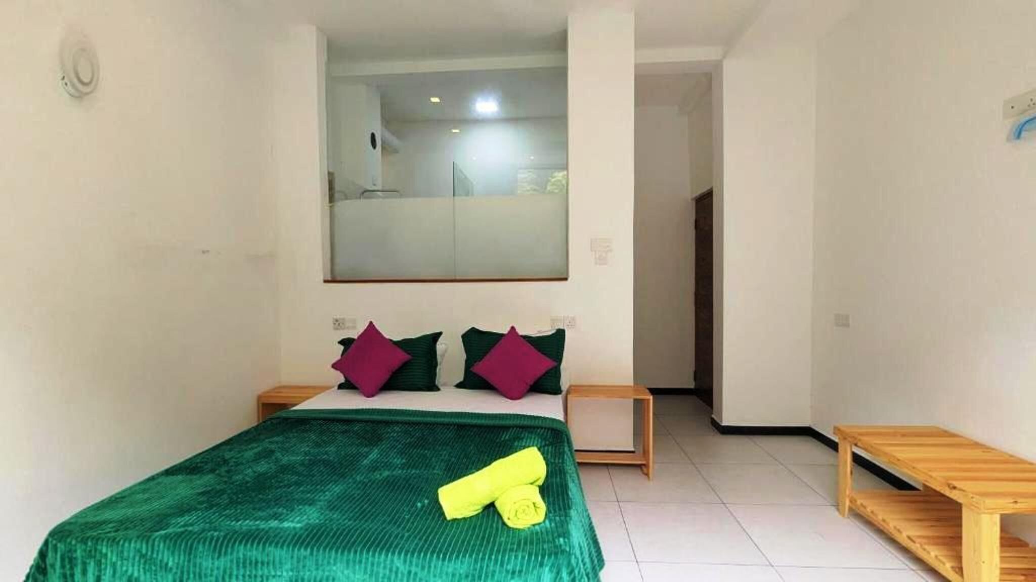 A bedroom with a bed, a mirror, and a wooden bench.