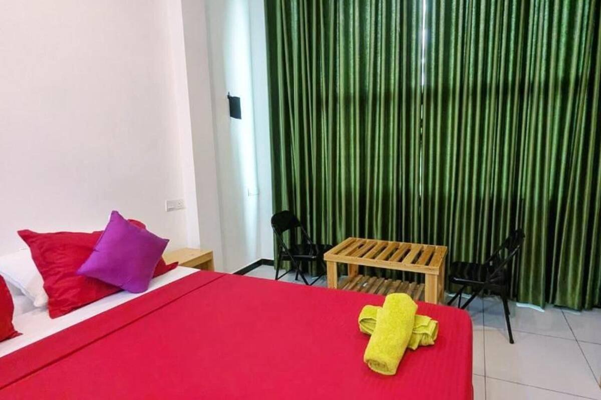 A room with a bed, a small table, two chairs, and a wooden wardrobe.