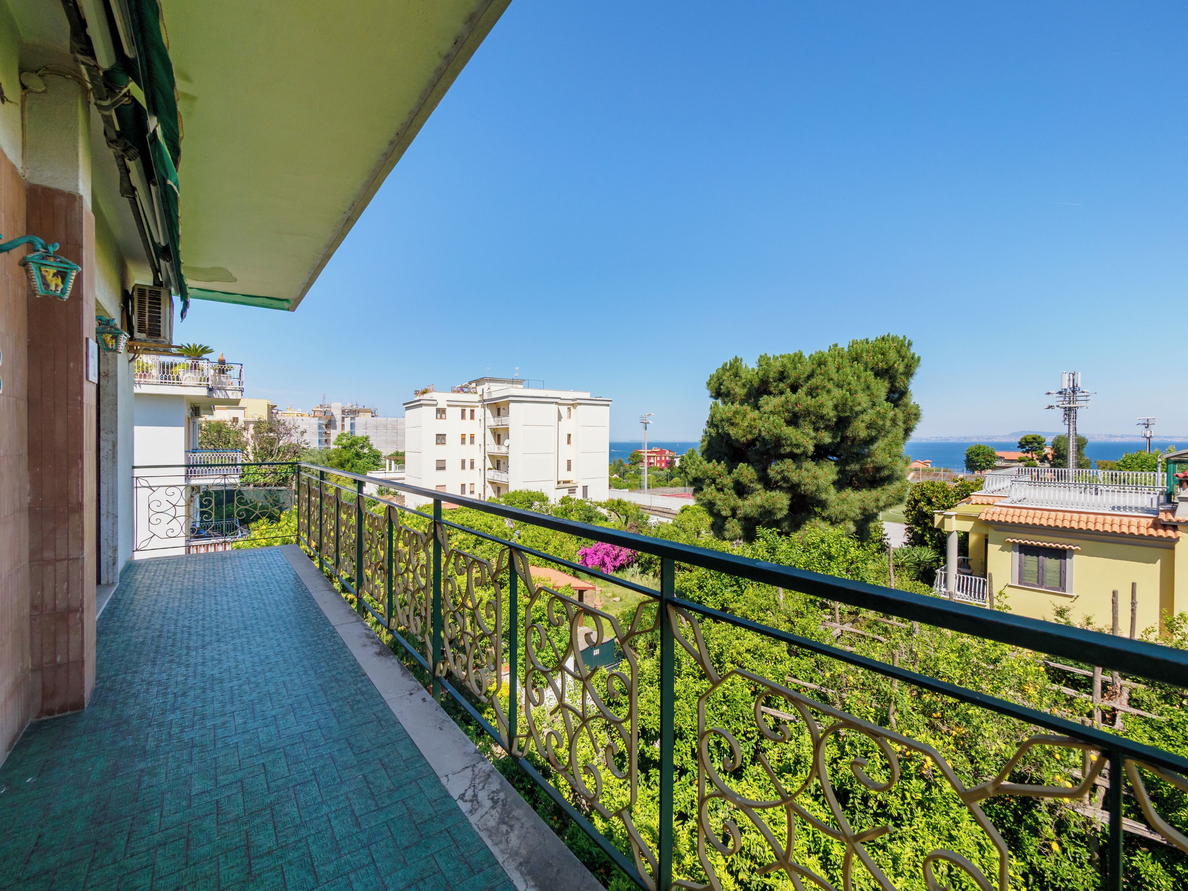 Un balcon avec vue sur la mer, les bâtiments et la verdure.