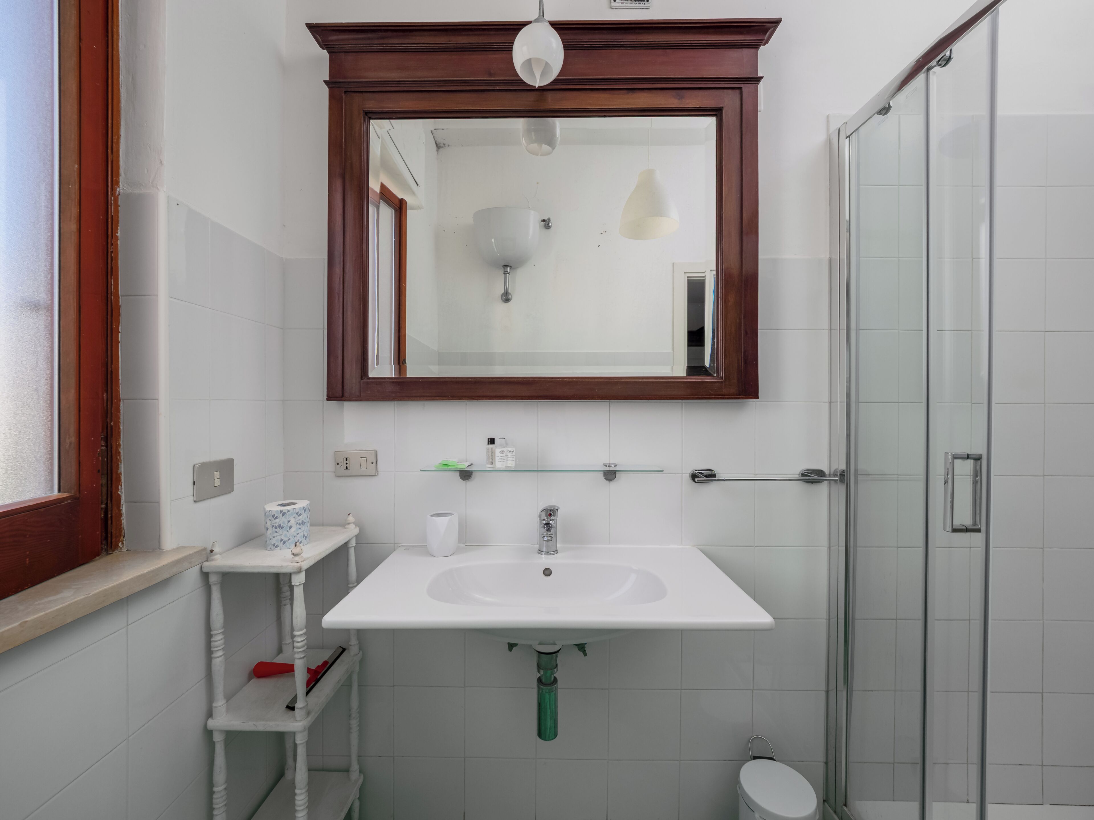 A bathroom with a white sink, a mirror above it, a shower, and a toilet.