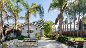 A residential property with a paved driveway, a stone planter, and a wooden fence.