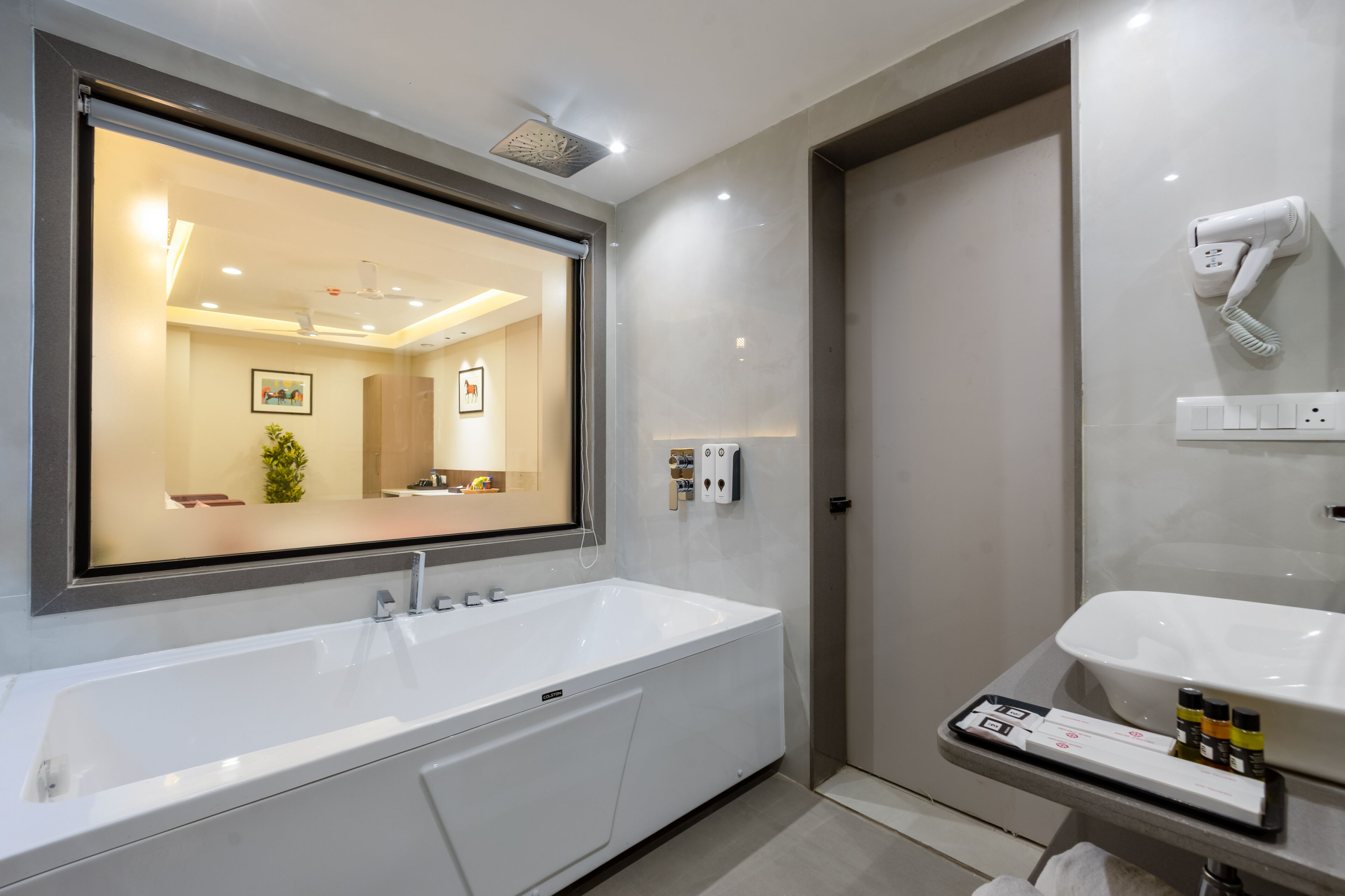 A modern bathroom with a large mirror, a bathtub, a shower, and a sink.