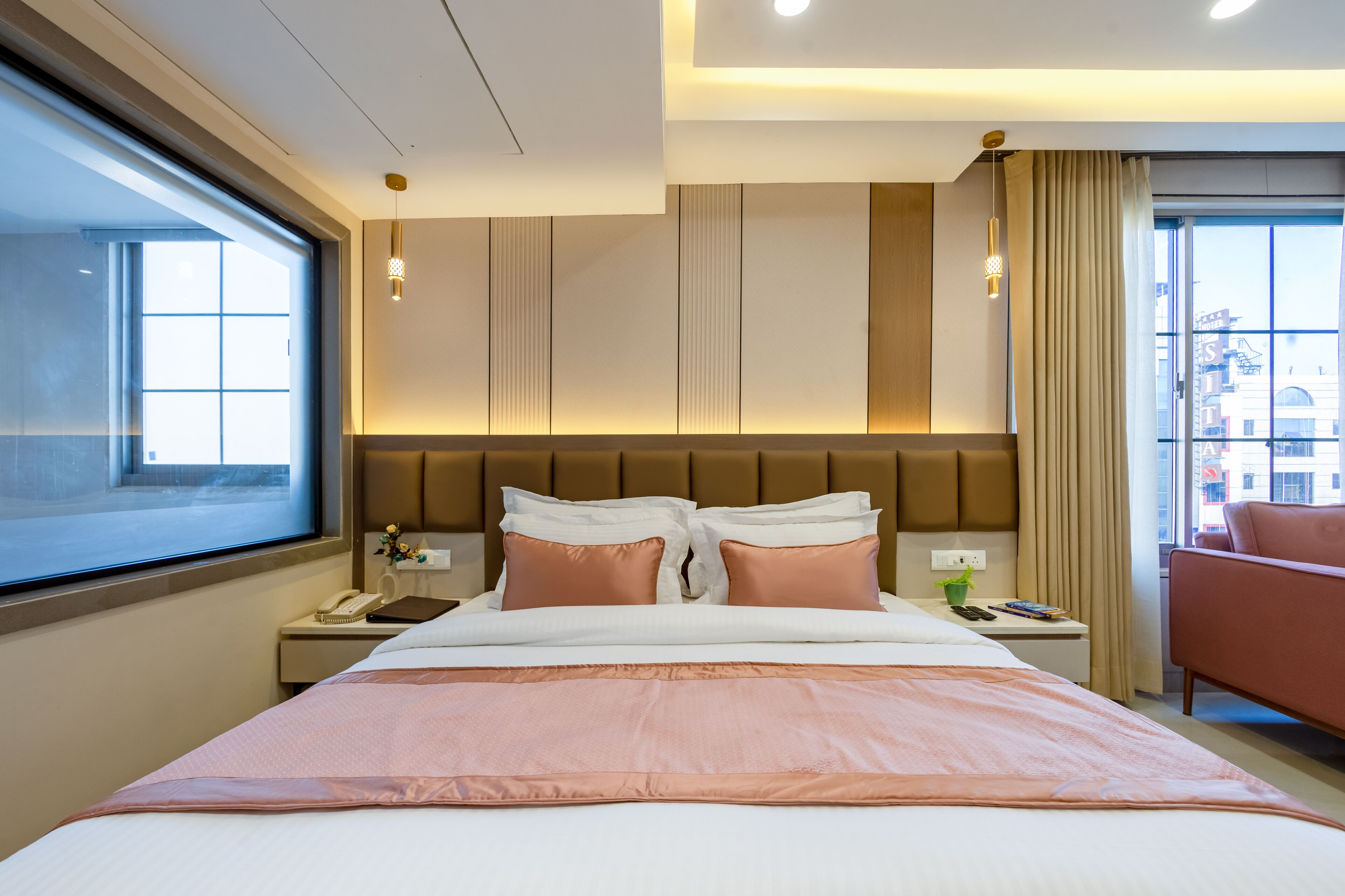 A hotel room with a large bed, a nightstand, a chair, and a window with a city view.