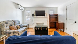 Una sala de estar con un sofá, un televisor sobre la chimenea y un mueble de madera.