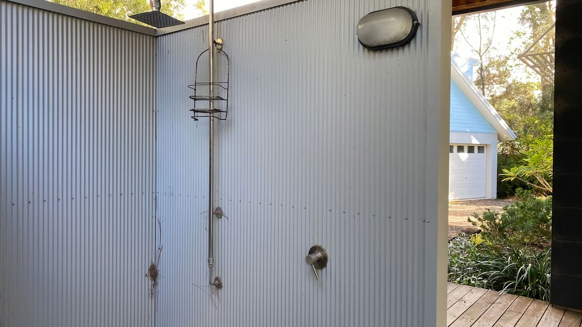A corrugated metal wall with a metal ladder, a door with a round handle, and a small window.