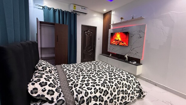 Ein Schlafzimmer mit Bett, einem an der Wand montierten Fernseher und einem Kleiderschrank.