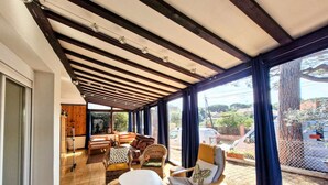 A spacious room with a high ceiling, large windows, and a view of the outside. There is a seating area with chairs and a small table. - House for 6 guests with air conditioning and Wi-Fi – Hyères Port (HYERES)